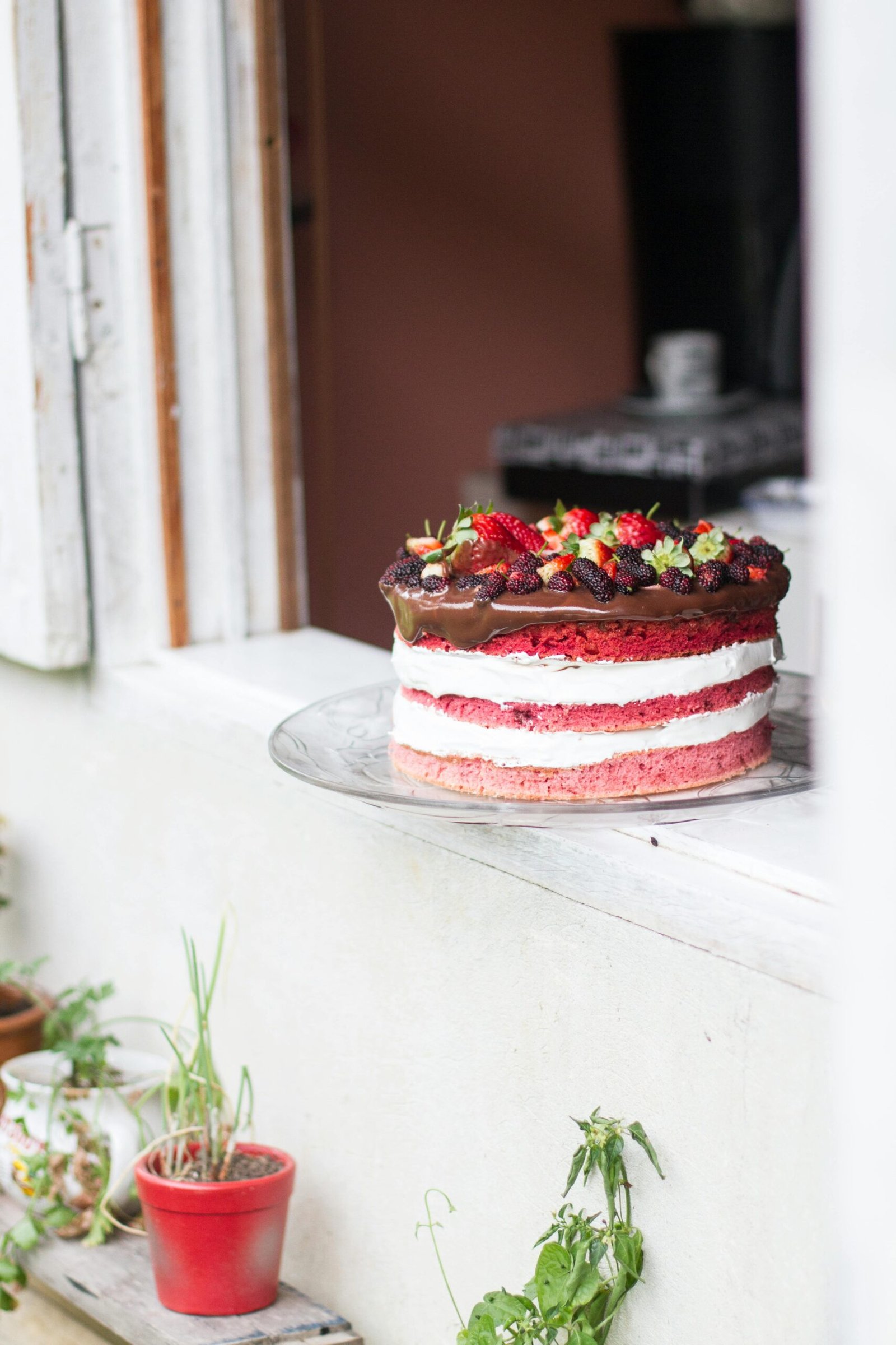 Enticing three-layer chocolate cake with strawberries and cream icing in a cozy setting.